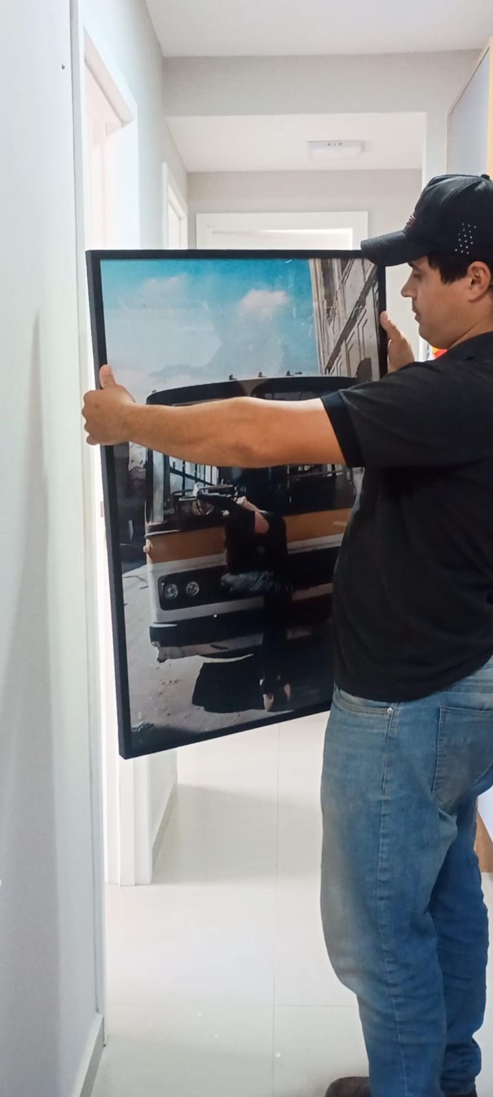 Profissional da JS Faz Tudo posicionando um quadro emoldurado na parede antes da fixação